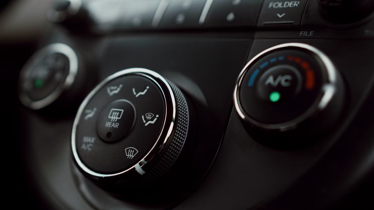 Detailed close-up of car dashboard air conditioning controls with focus on buttons and dials.